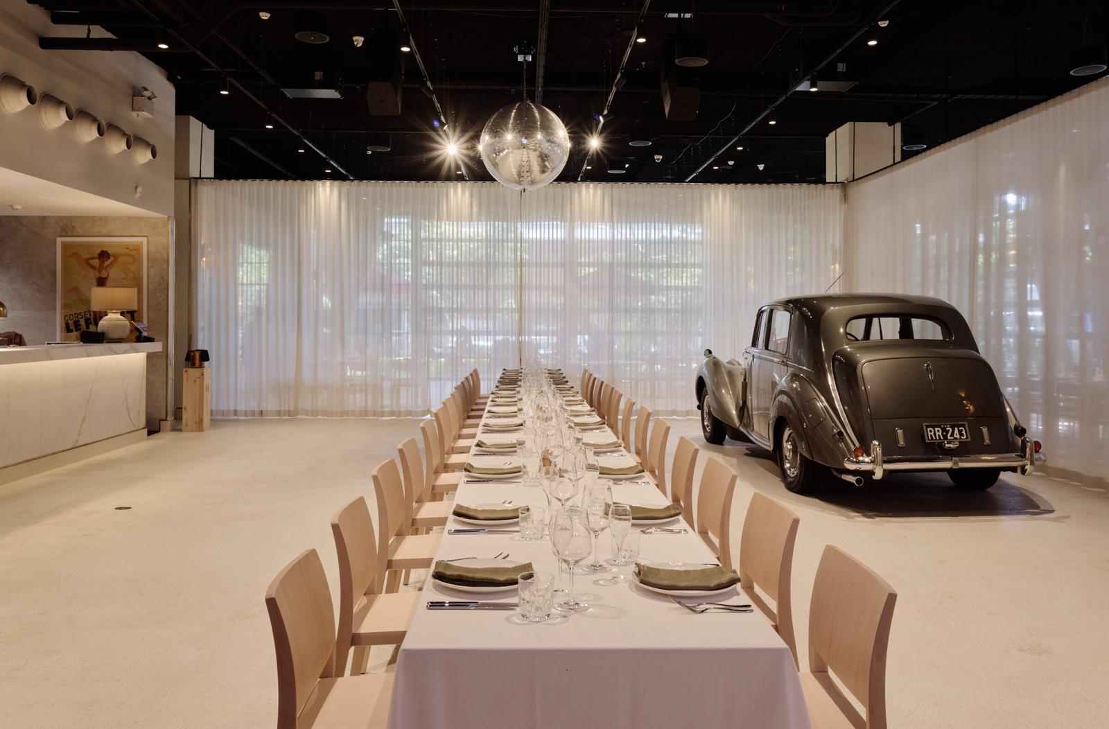 A long banquet table set for a private event at Verde Alexandria, a classic car beneath a mirror ball