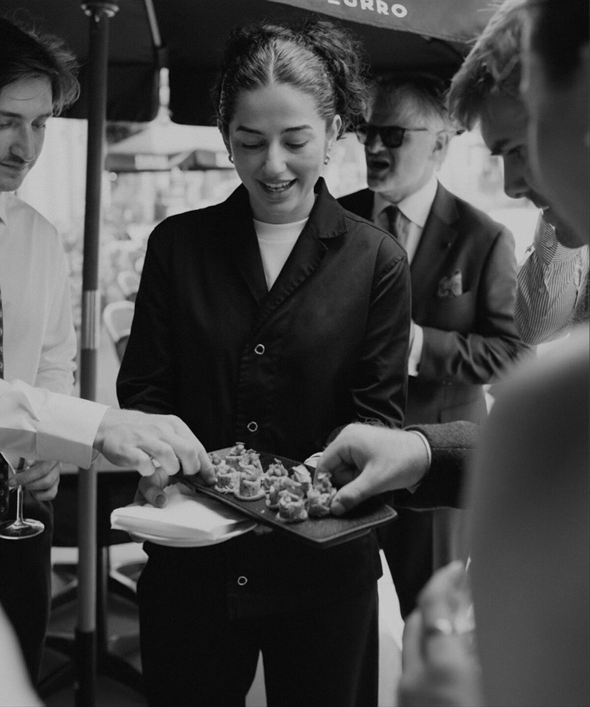 A Verde host passing a tray of canapes to guests at an event
