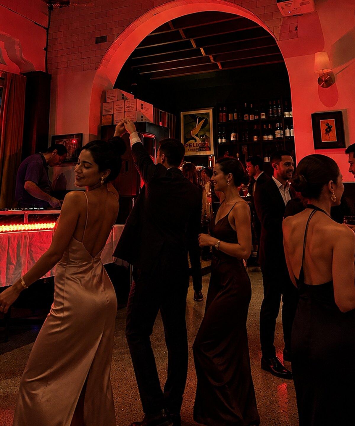 Guests in evening dress at a private event at Verde, under warm red light