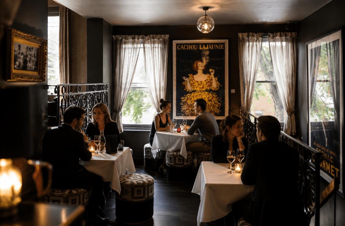 The Upstairs private dining room, sandstone walls, white tablecloths, Cachou Lajaunie poster